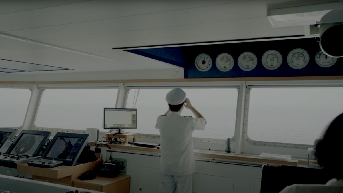 Ships captain at windows looking through binoculars.