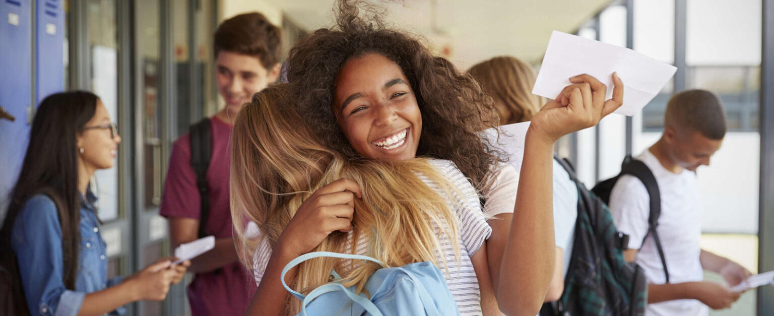 High school students happily hugging in the hallway.