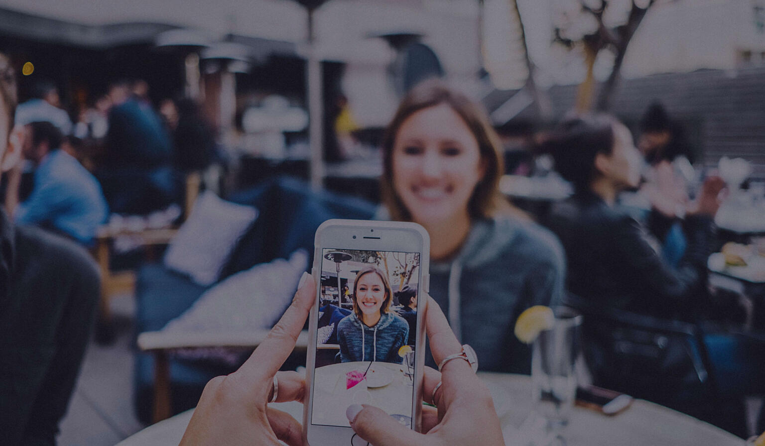 Someone taking a picture of their dining companion using a cell phone.