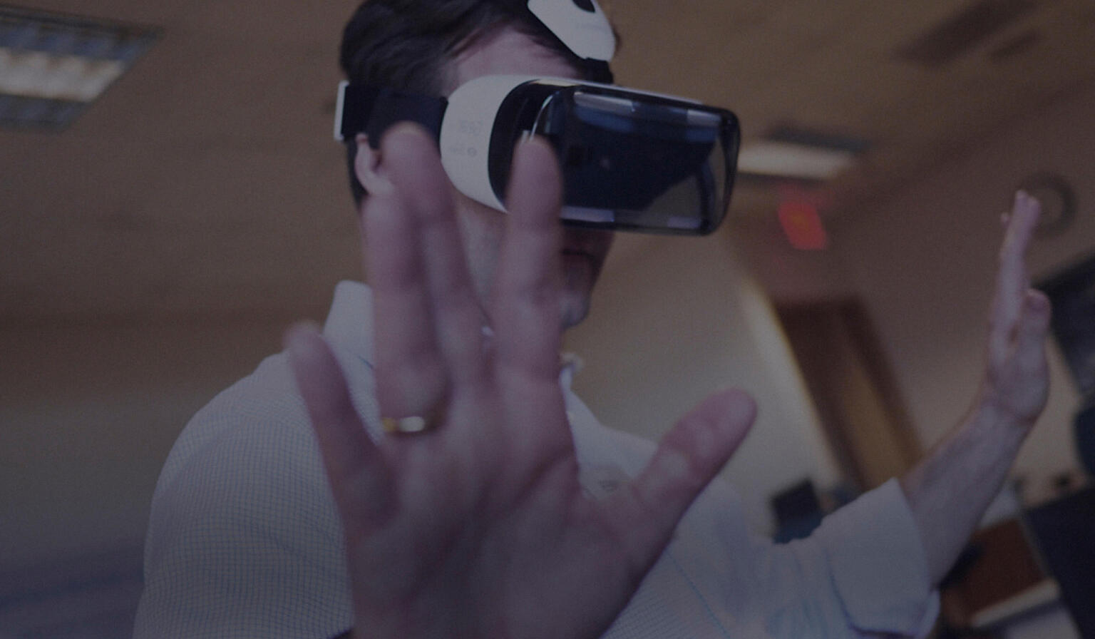 Man wearing a VR headset, hands outstretched reacting to game play.