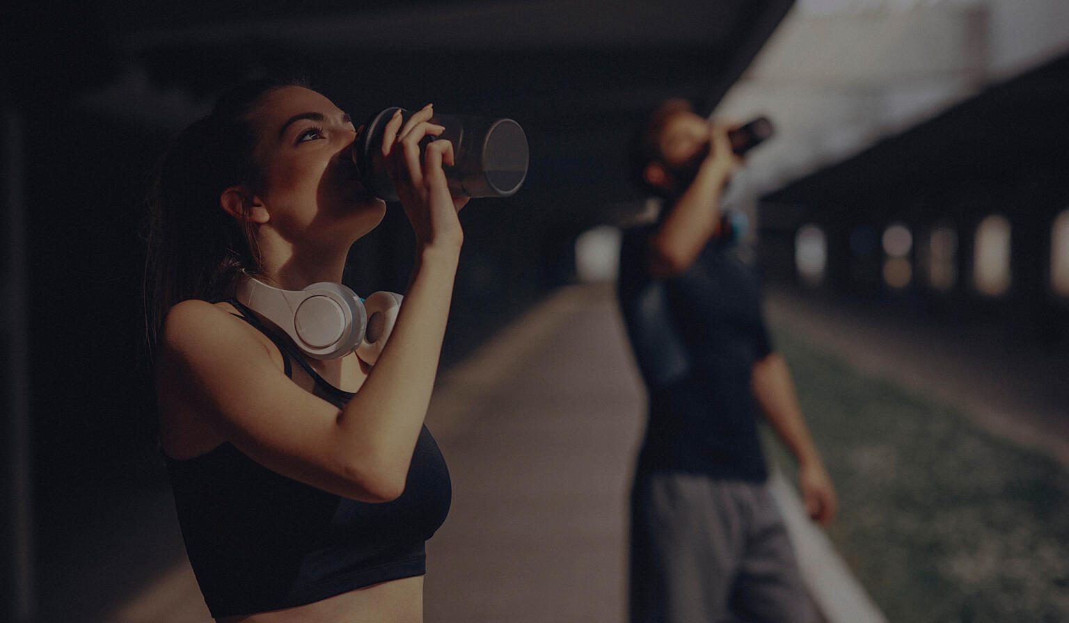 Man and woman post workout drinking from water bottles.