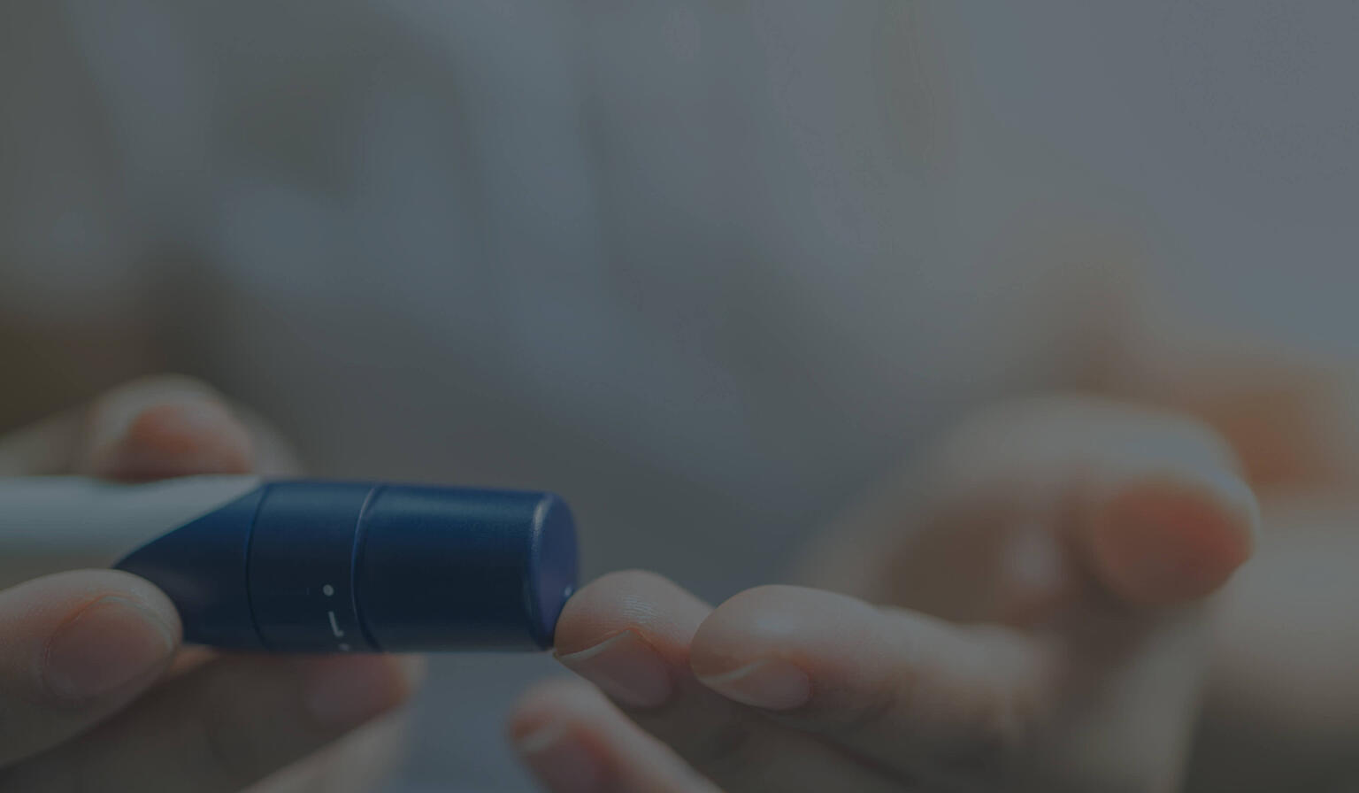 Close up of person using a finger prick device for diabetic blood testing.