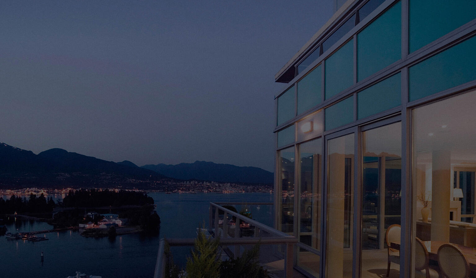 Deck of a modern high-rise building overlooking marina, harbor, and mountains.
