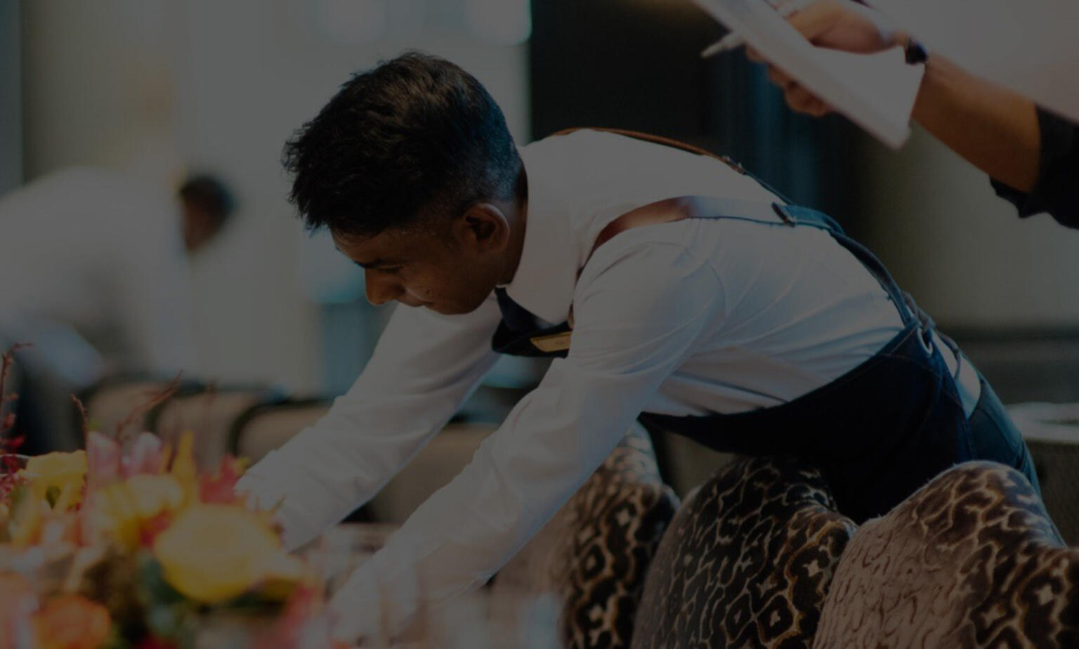 Waiter bending over to set a large table.