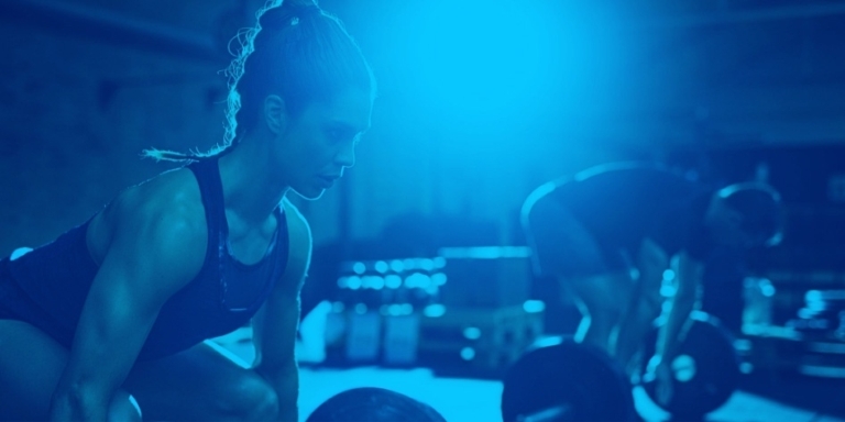 Blue duotone of woman and man lifting barbells.
