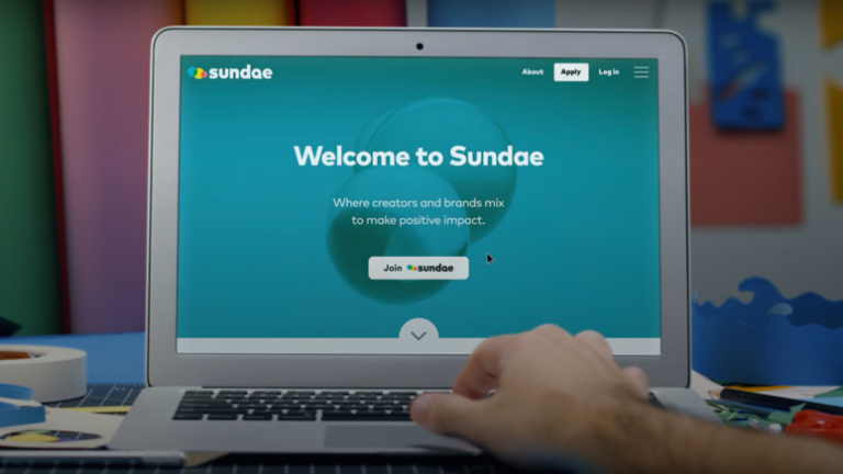 hand using a laptop with 72and Sunny Sundae app loading.
